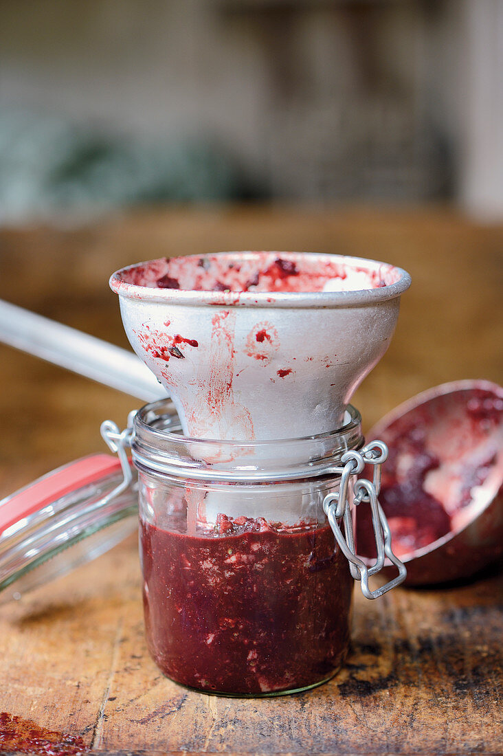 Tongue and heart black pudding being made: mixture being transferred to a flip-top jar