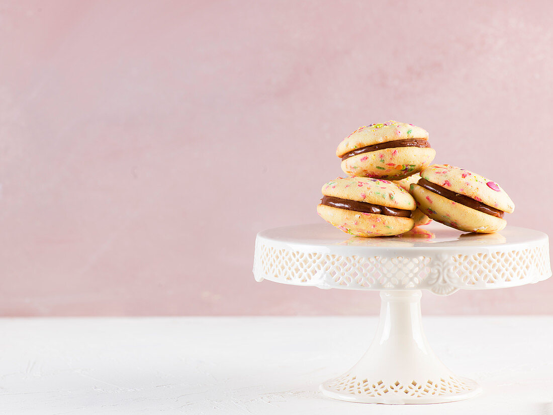 Whoopie pies with colourful sugar sprinkles on a cake stand