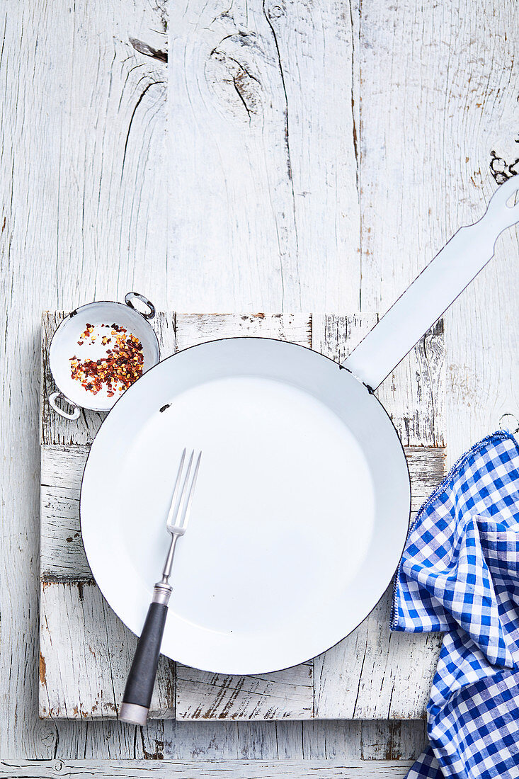 Empty frying pan on white wooden surface