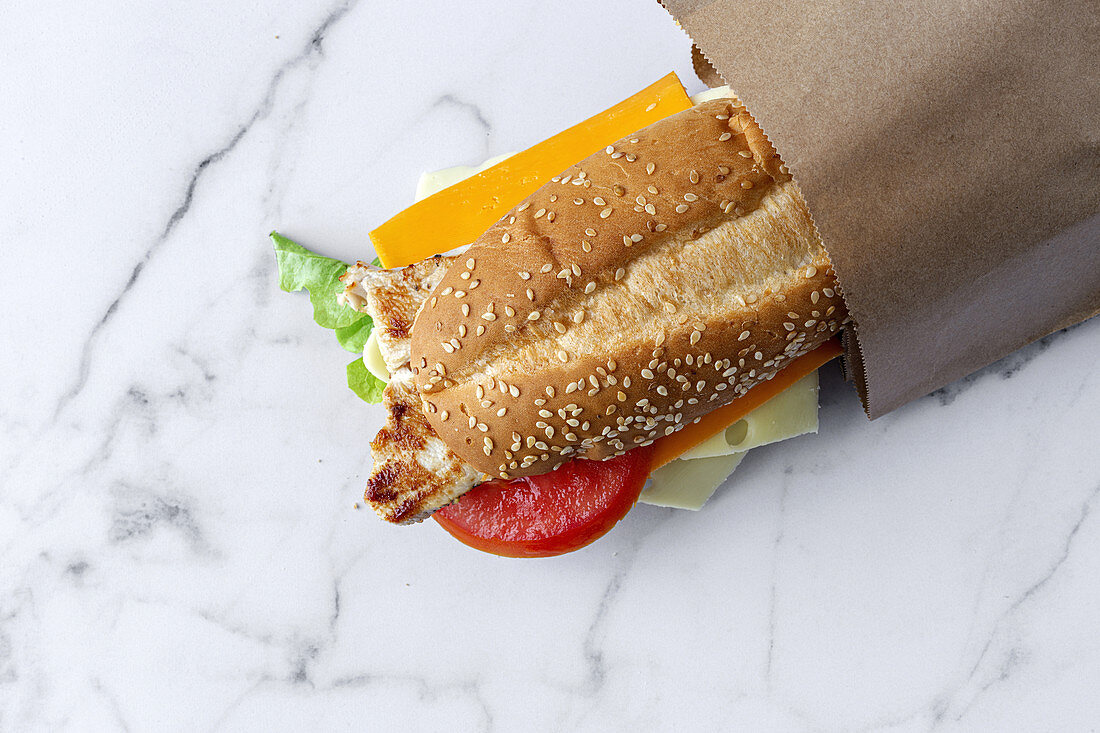 Sandwich mit Käse und Gemüse in Papiertüte zum Mitnehmen