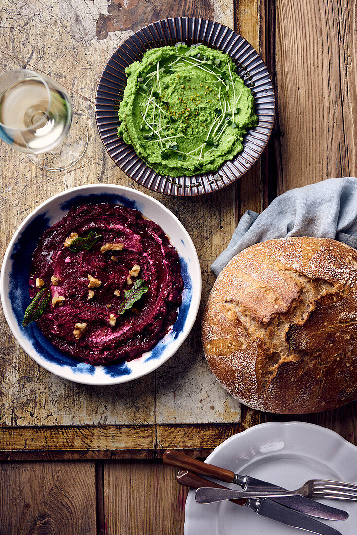 A pea dip and a beetroot dip next to a loaf of sourdough bread