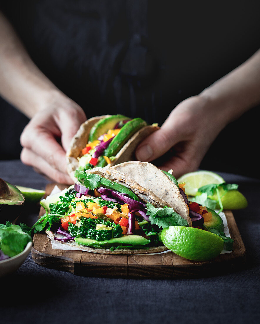 Vegetarian tacos with kale, lime, avocado, taco sauce, cilantro, and bell pepper