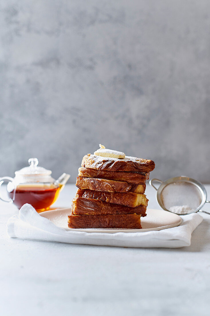 A pile of french toasts for breakfast with butter and powdered sugar
