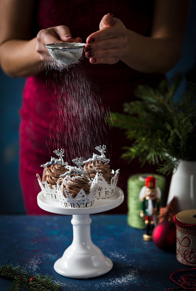 Weihnachtscupcakes mit Puderzucker bestäuben