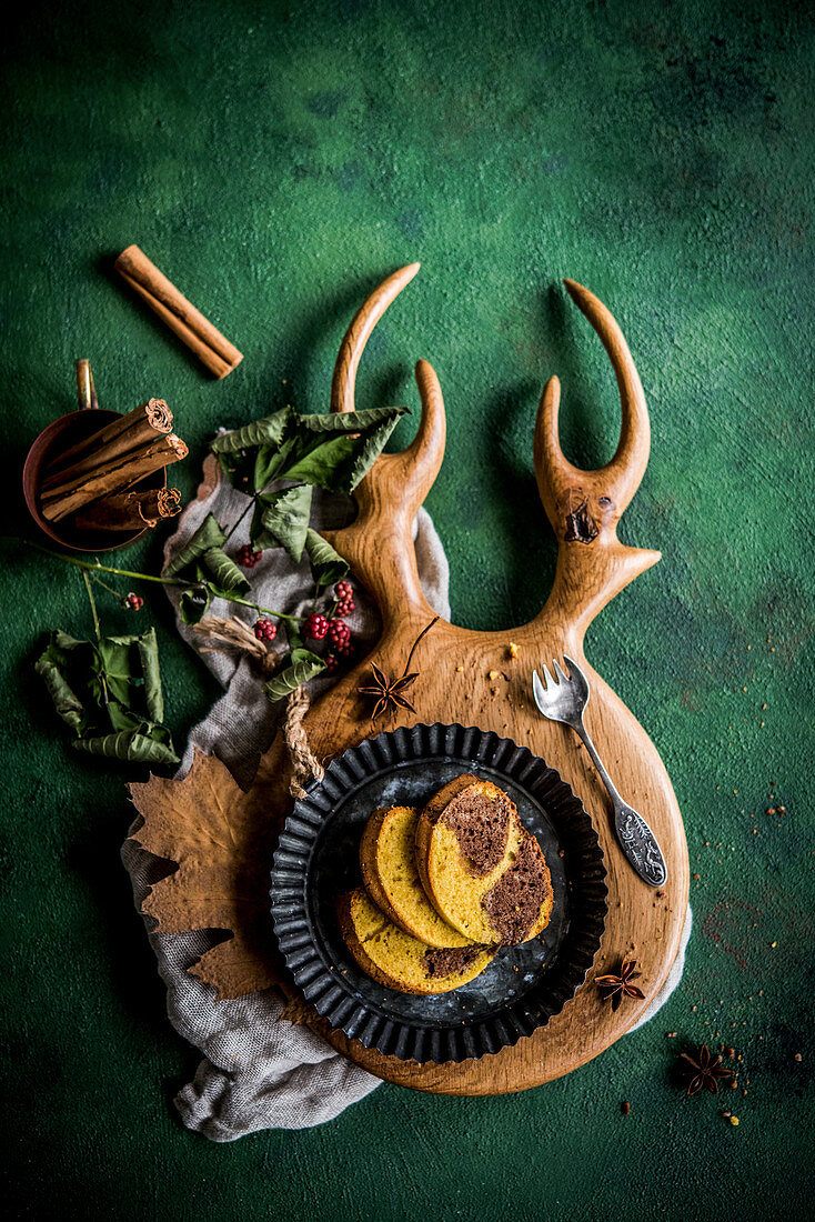Herbstlicher Kürbis-Kakao-Kuchen mit Zimt auf geweihförmigem Holzbrett