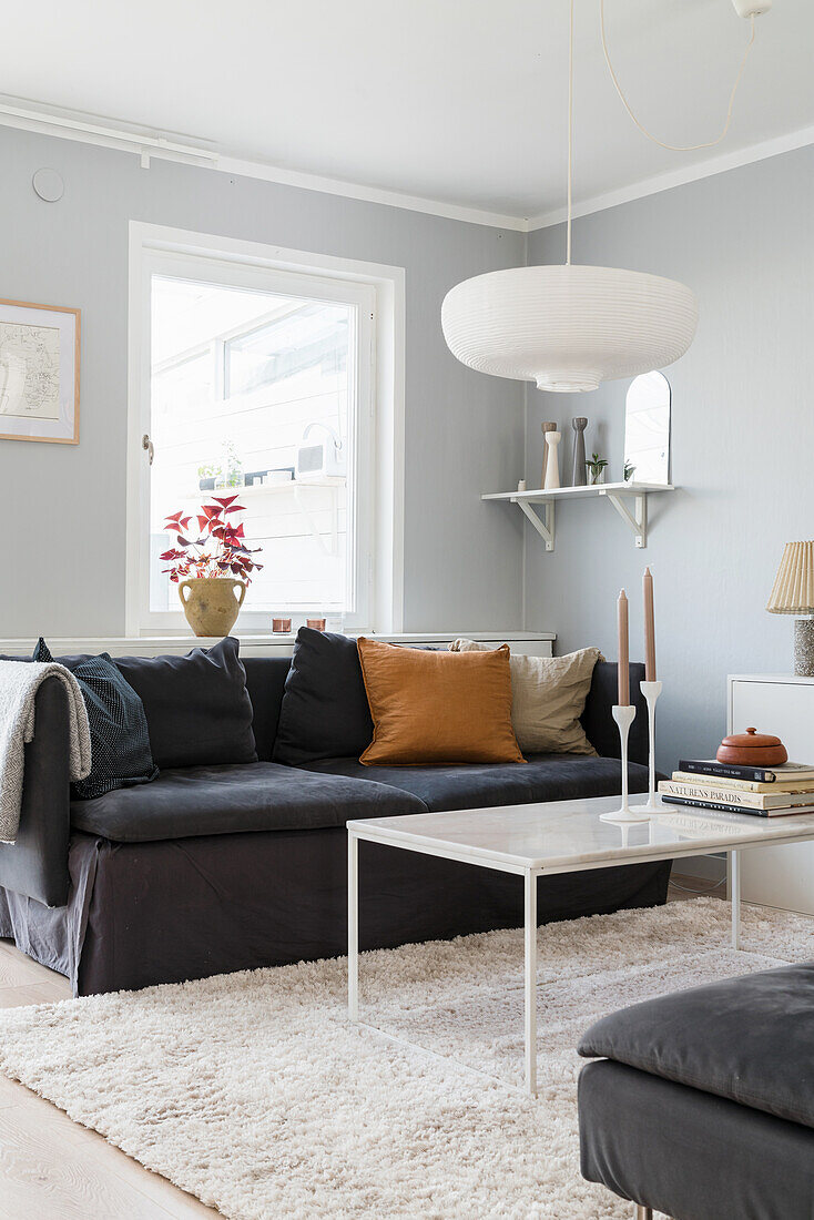 Sofa with scatter cushions and white coffee table in living room with light grey walls