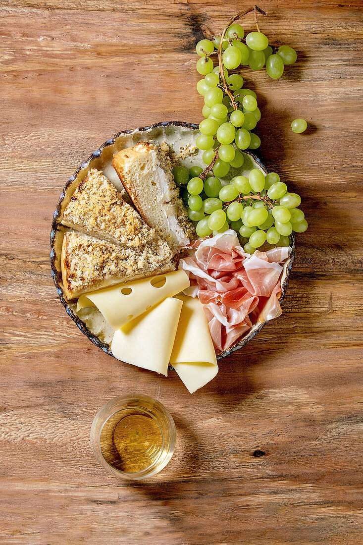 Antipasti mit weißer sizilianischer Focaccia, Prosciutto, Käse und Trauben (Italien)