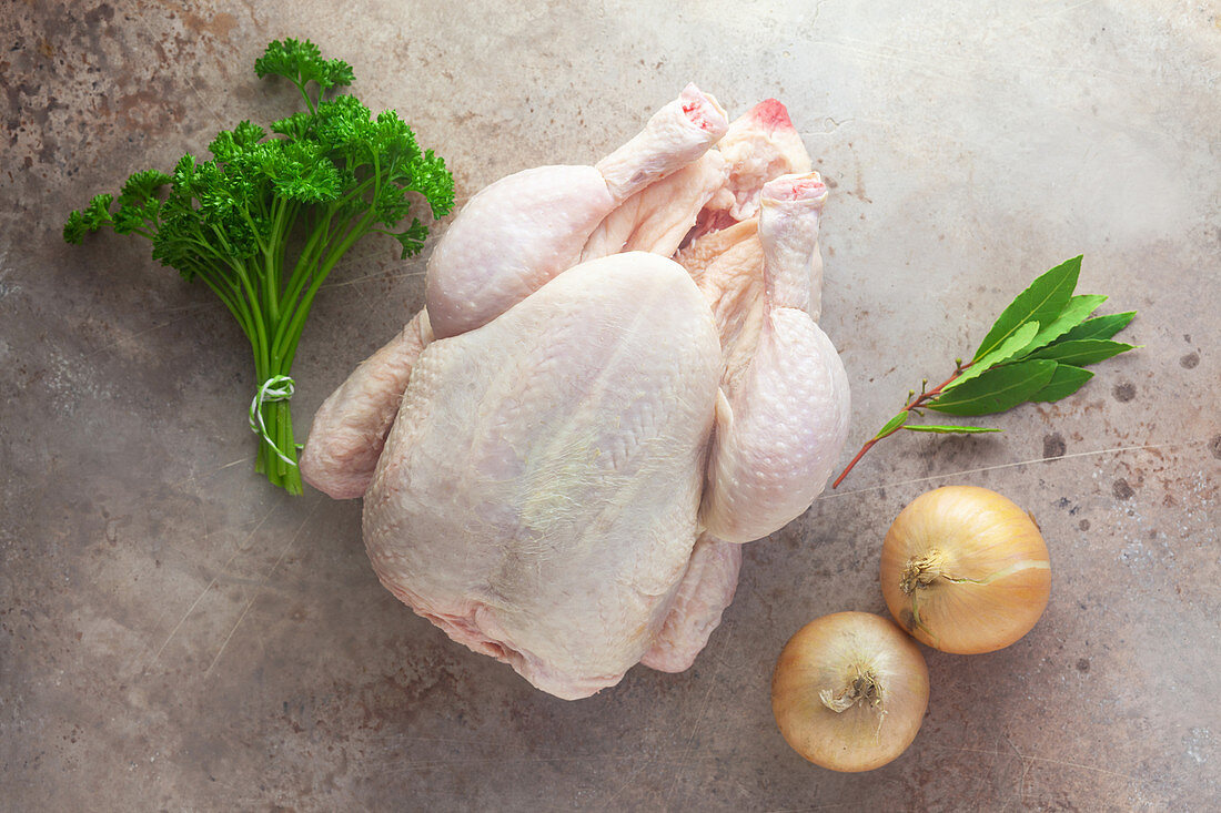 Zutaten für Hühnerbrühe: Ganzes rohes Huhn, Kräuter und Zwiebeln