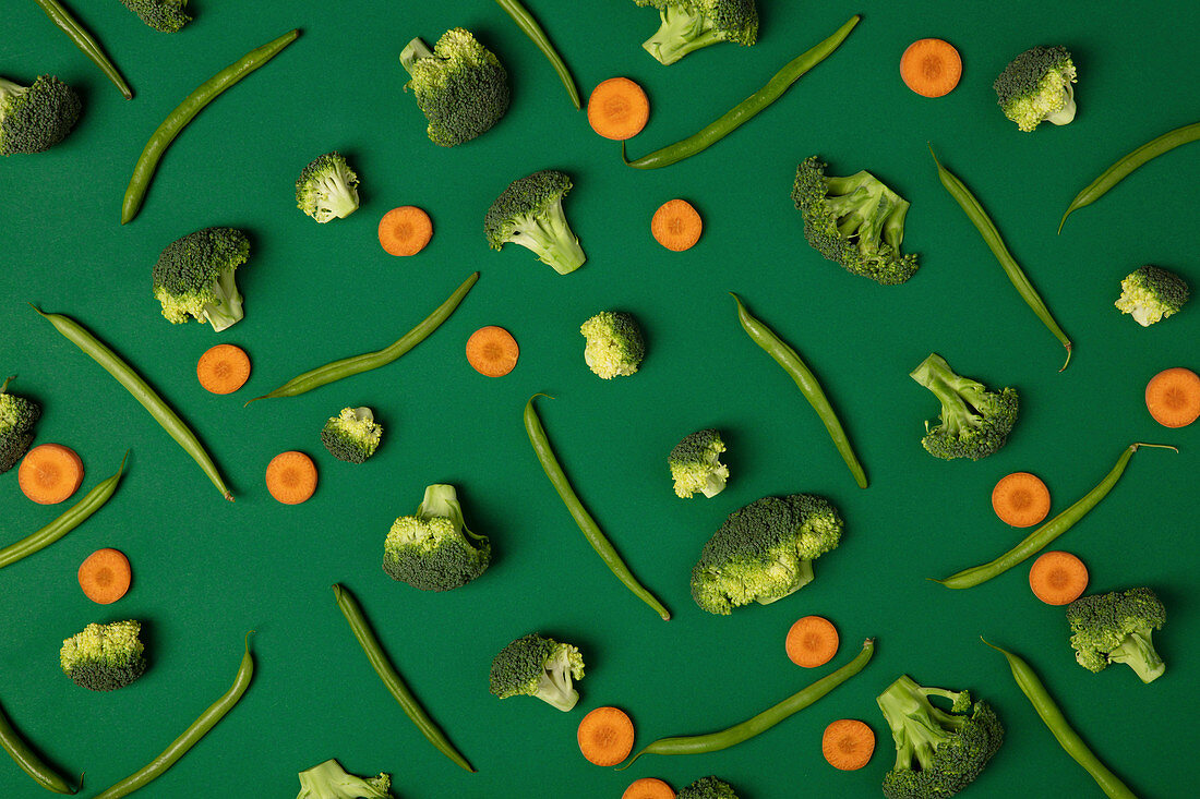 Broccoli, carrots and green beans on green background