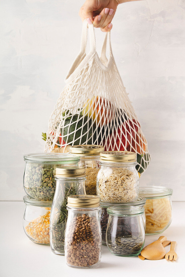 Fruits and vegetables in reusable bags and glass jars with pasta, lentils, beans, rice, dry herbs