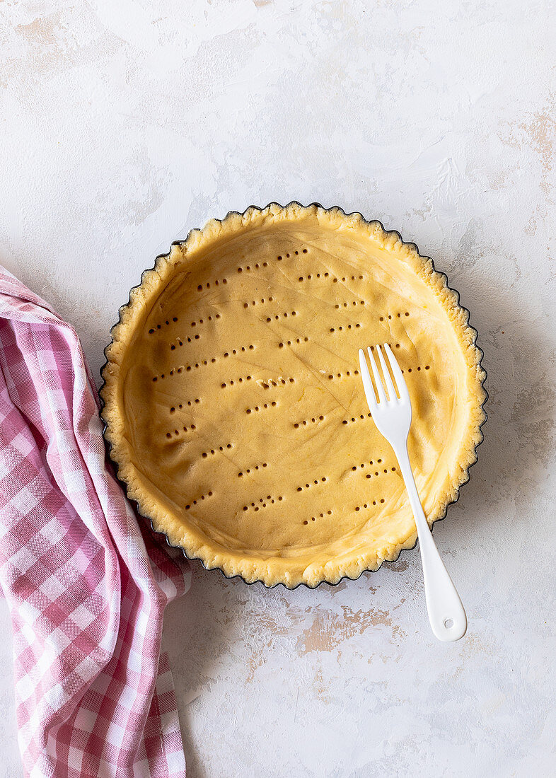 Preparing a tart: Pricking a short pastry base with a fork