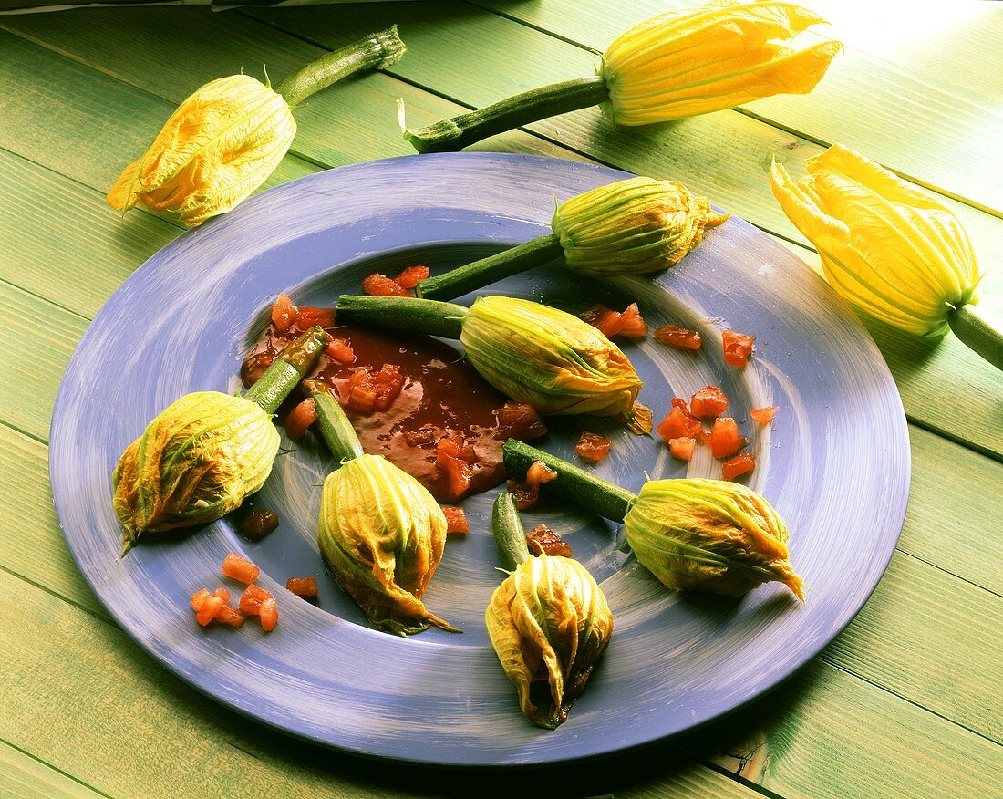 Gefüllte Zucchiniblüten mit Tomatensauce auf blauem Teller