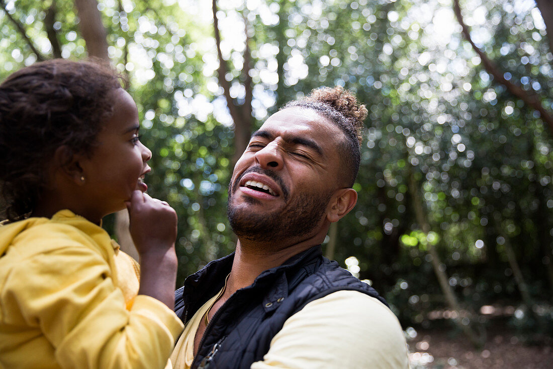 Playful father holding daughter in woods