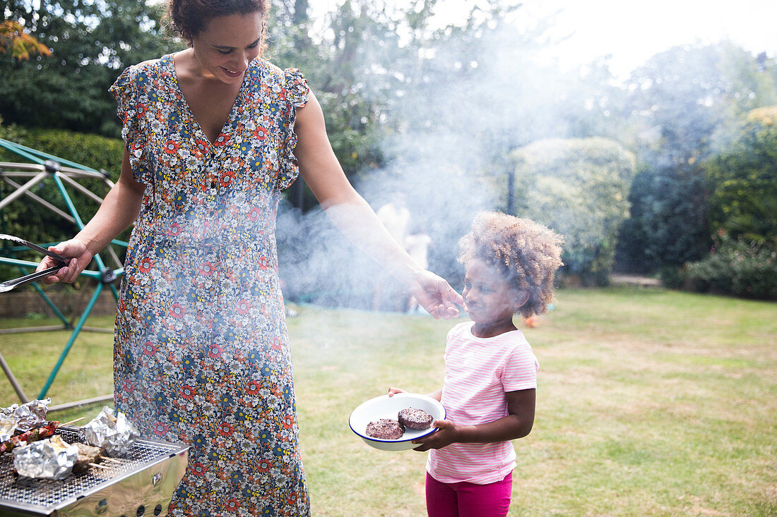Mother and daughter barbecuing in summer backyard
