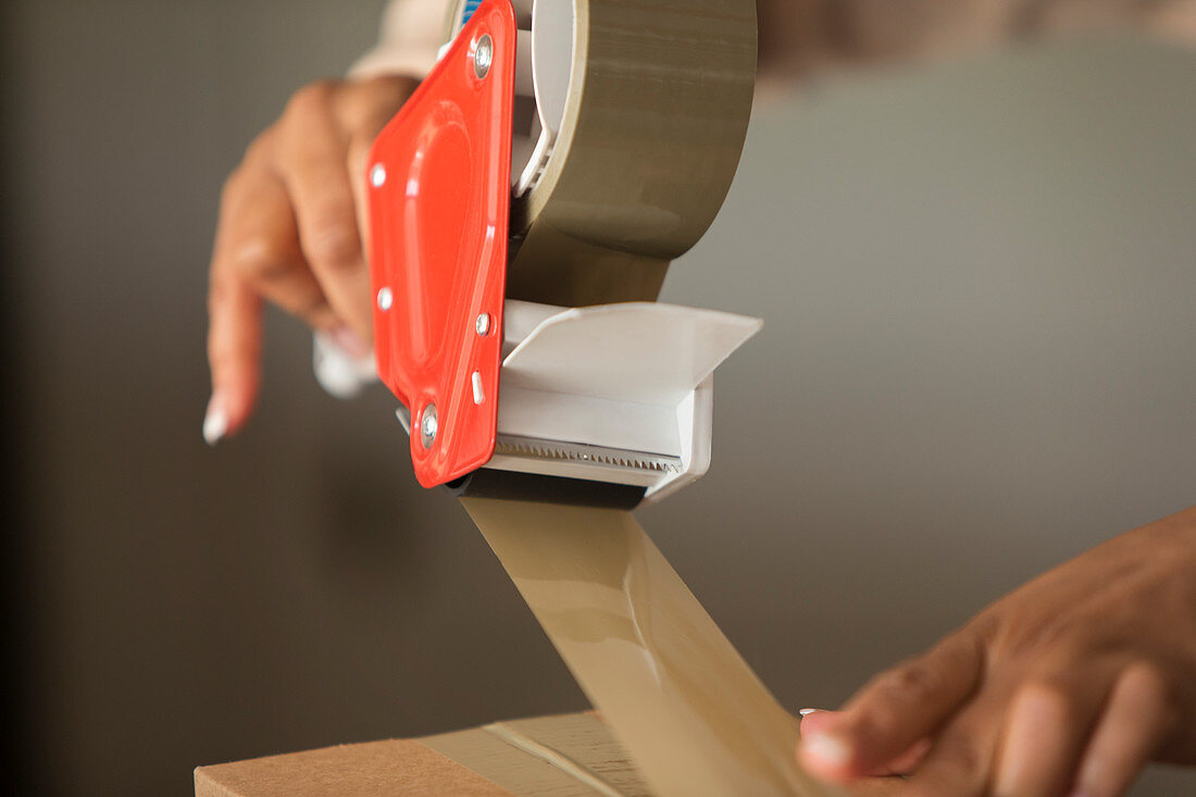 Close up female shop owner taping package for shipping