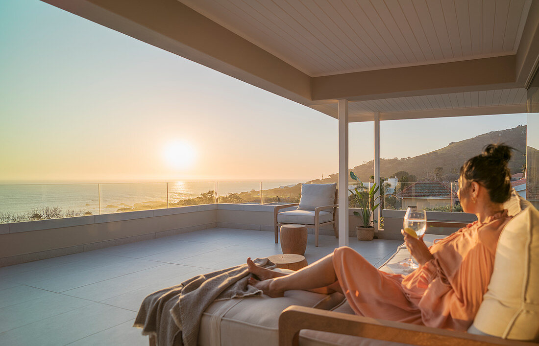Woman enjoying white wine and sunset ocean view
