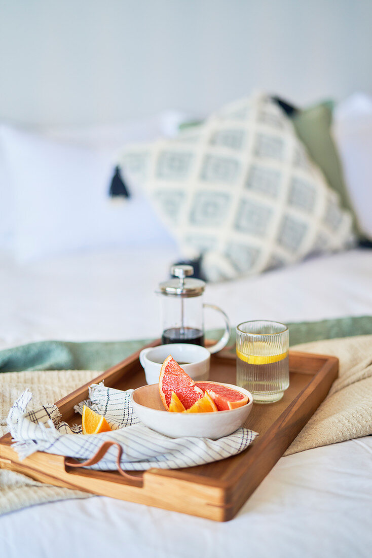 Grapefruit and coffee breakfast tray on morning bed