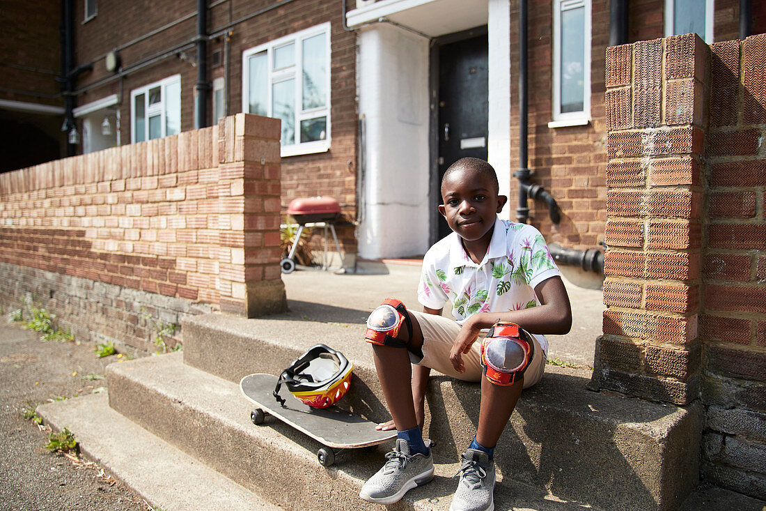 Portrait confident boy with skateboard on front stoop