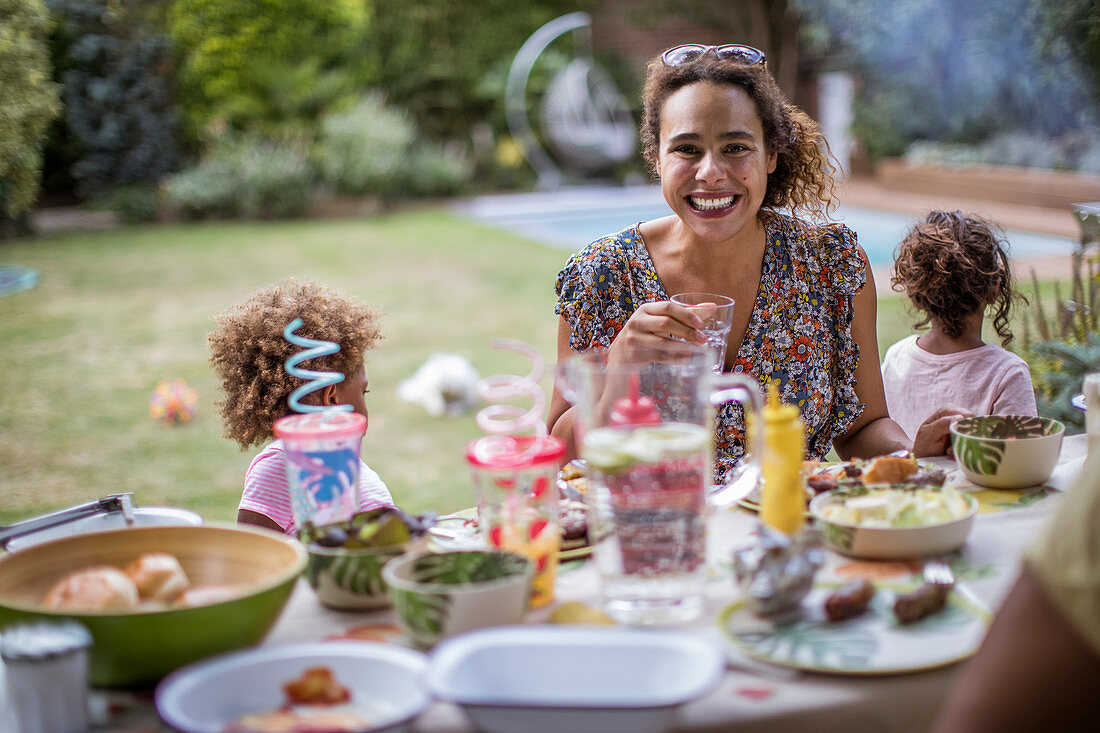 Mother enjoying summer barbecue with family on patio