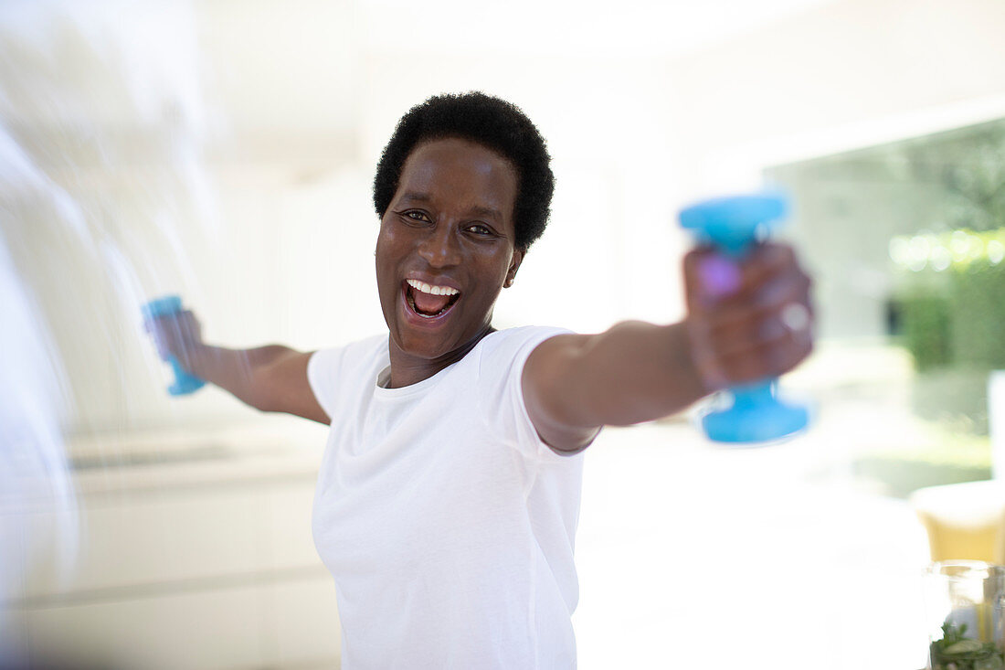 Portrait mature woman exercising with dumbbells at home