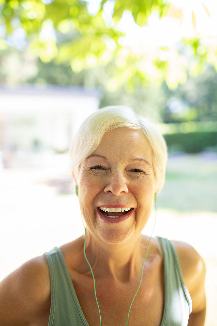 Portrait happy senior woman with headphones in garden