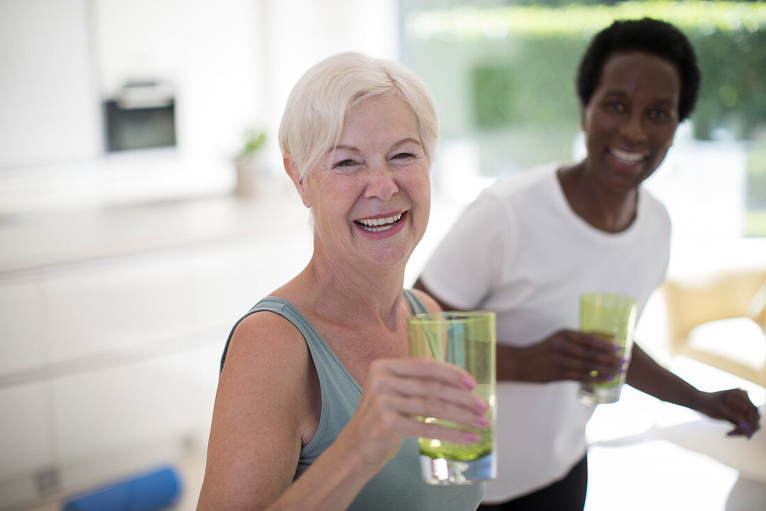 Portrait senior women friends drinking water at home