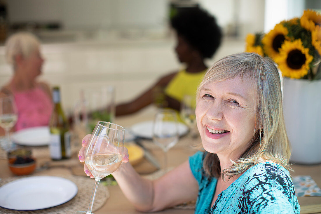 Senior woman drinking white wine with friends at table