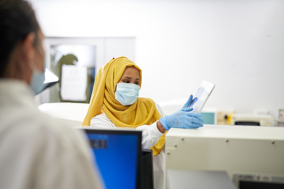 Scientist in hijab and face mask using digital tablet