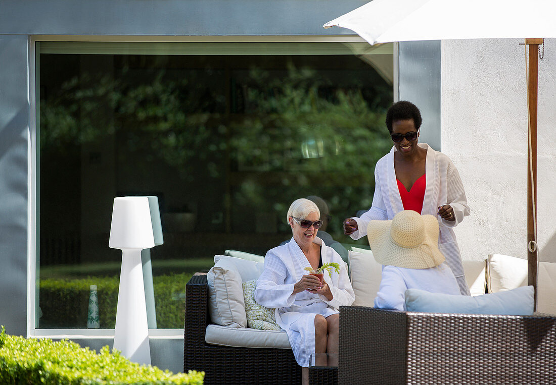 Senior women friends relaxing in spa bathrobes on patio
