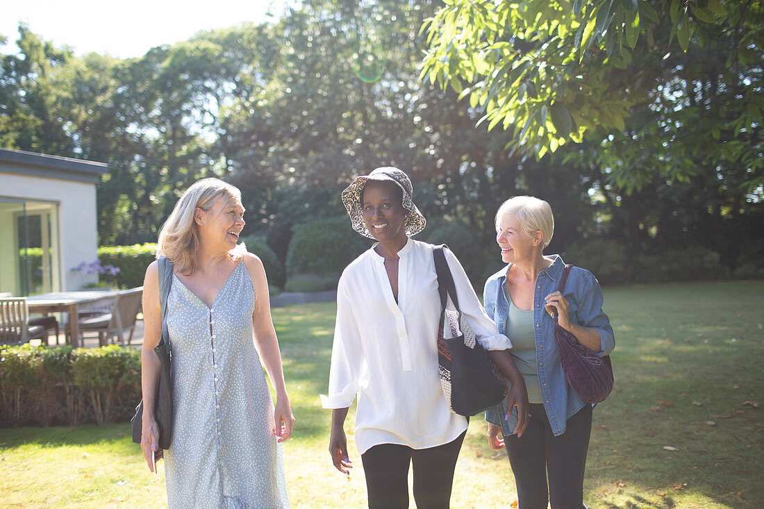 Happy senior women friends walking in summer garden