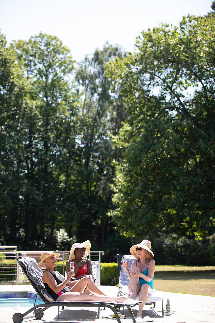 Senior women friends sunbathing drinking champagne