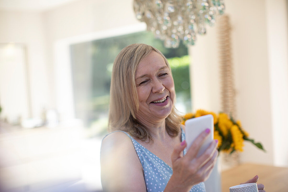 Smiling senior woman with smart phone at home