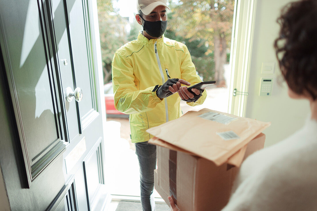 Woman receiving packages from delivery man in face mask