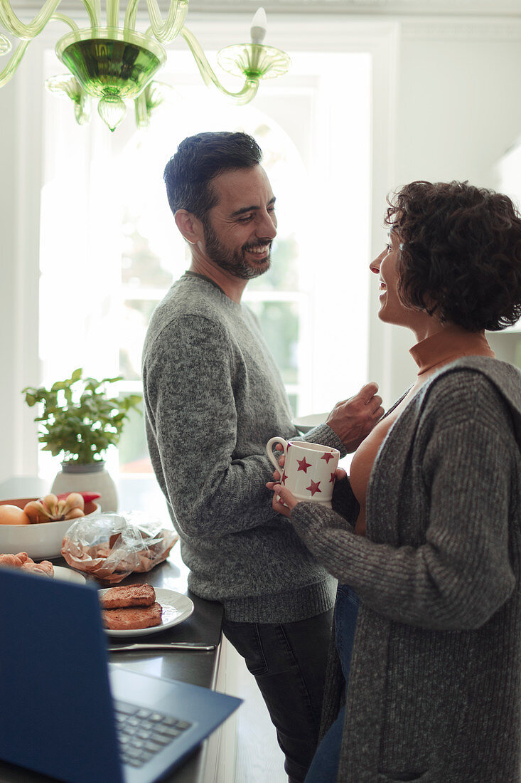 Couple talking and drinking coffee in morning kitchen