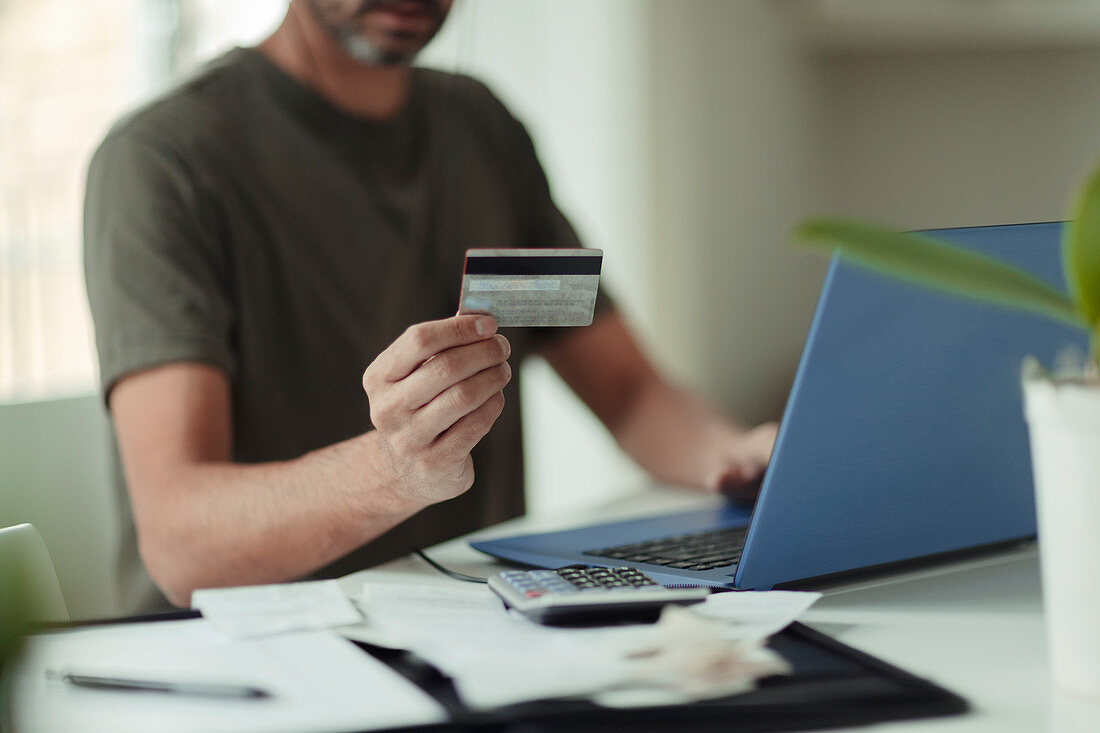 Man with credit card online shopping at laptop