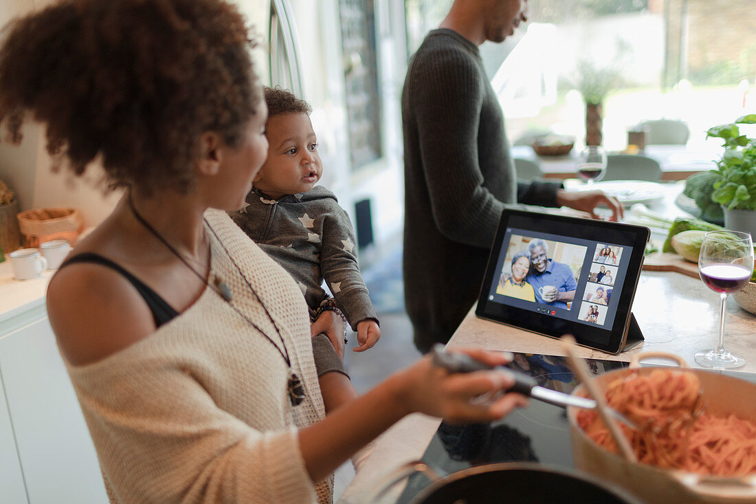 Family cooking dinner and video chatting by digital tablet