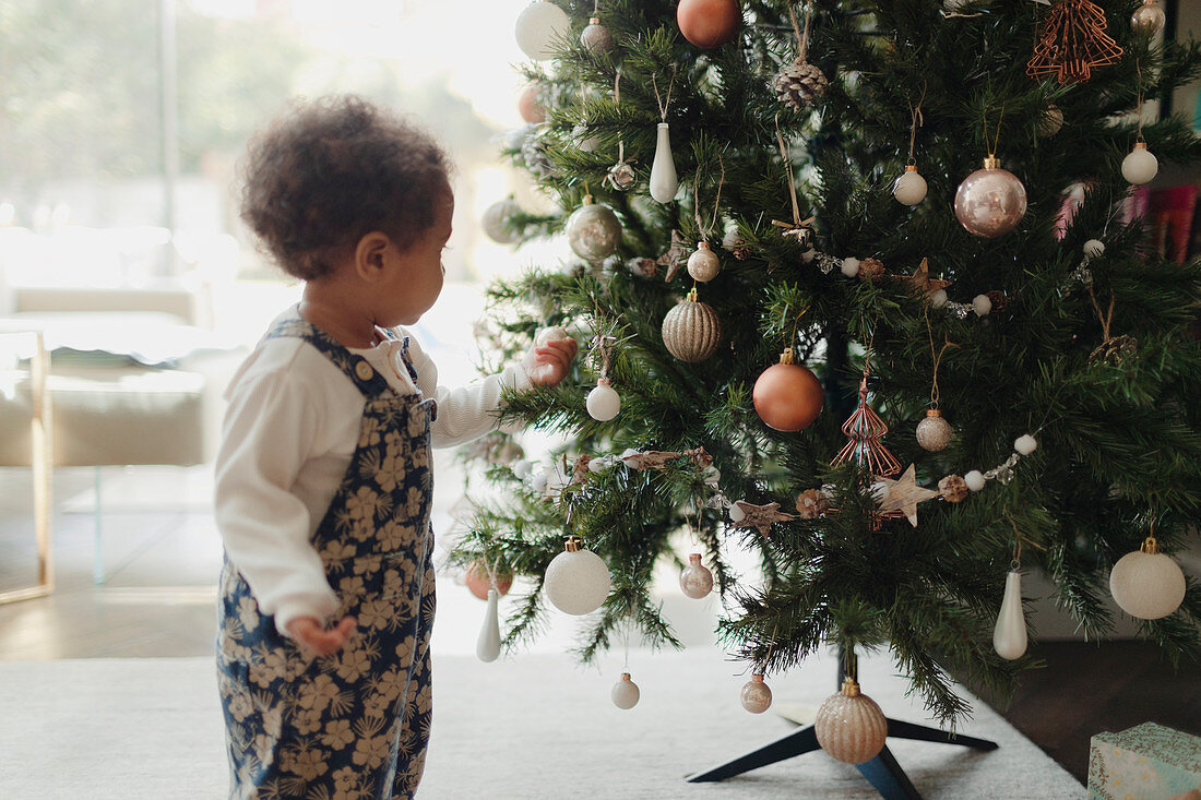 Cute baby girl looking at Christmas tree decorations