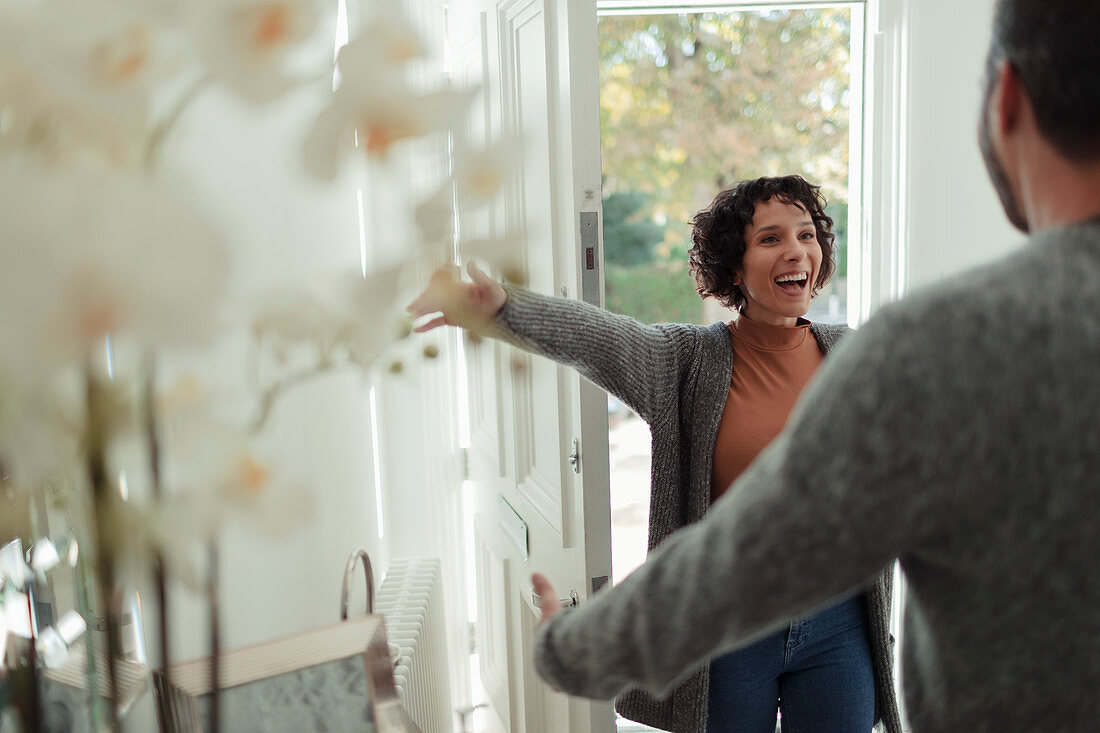 Happy husband greeting excited wife at front door