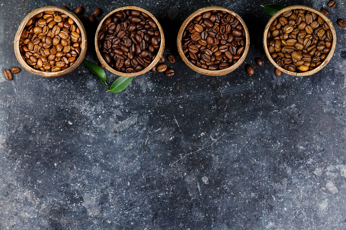 Vier verschiedene Sorten von Kaffeebohnen in Holzschalen