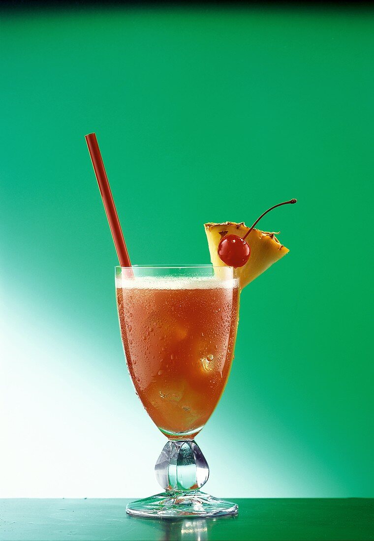 A glass of Planter's Punch with straw, pineapple, cherry