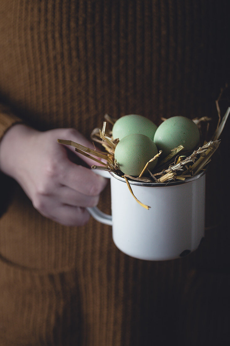 Woman holding a cup with green hen's eggs
