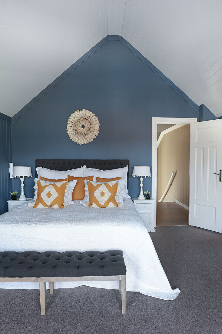 Double bed and bedroom bench in attic bedroom with blue walls