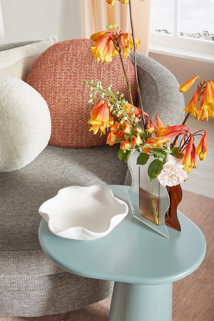 Flowers in wavy vase on light blue side table