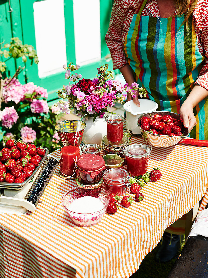Selbstgemachte Erdbeermarmelade und frische Früchte auf Tisch im Garten