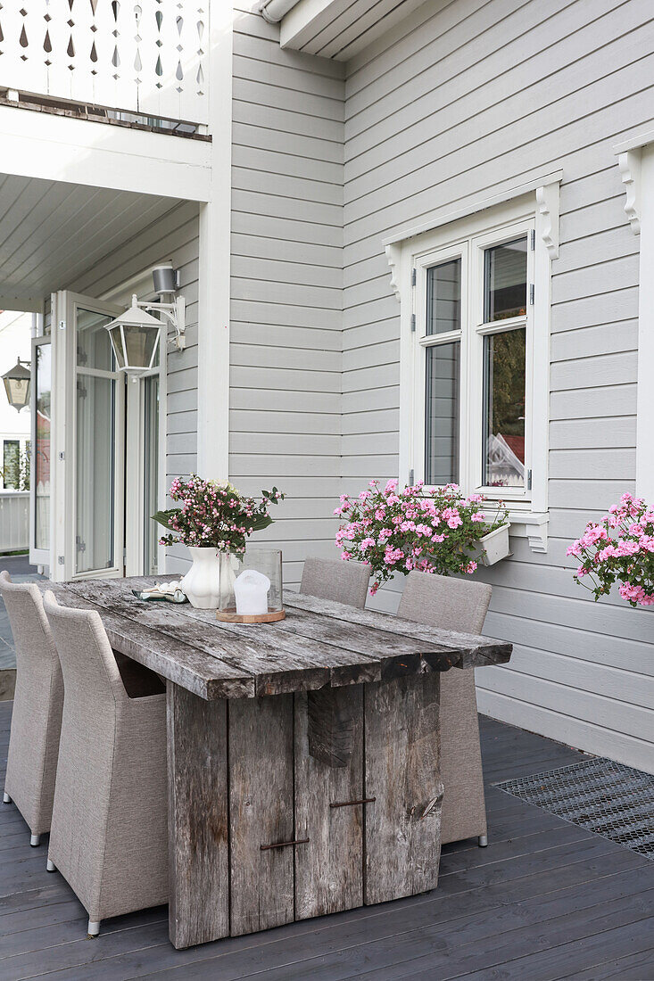 Rustikaler Holztisch mit eleganten Rattanstühlen auf der Terrasse