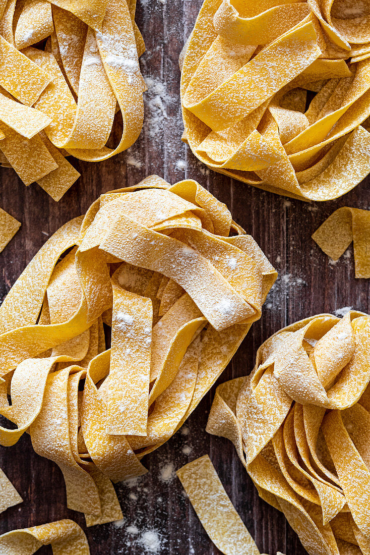 Ungekochte Tagliatelle-Nester auf Holzuntergrund