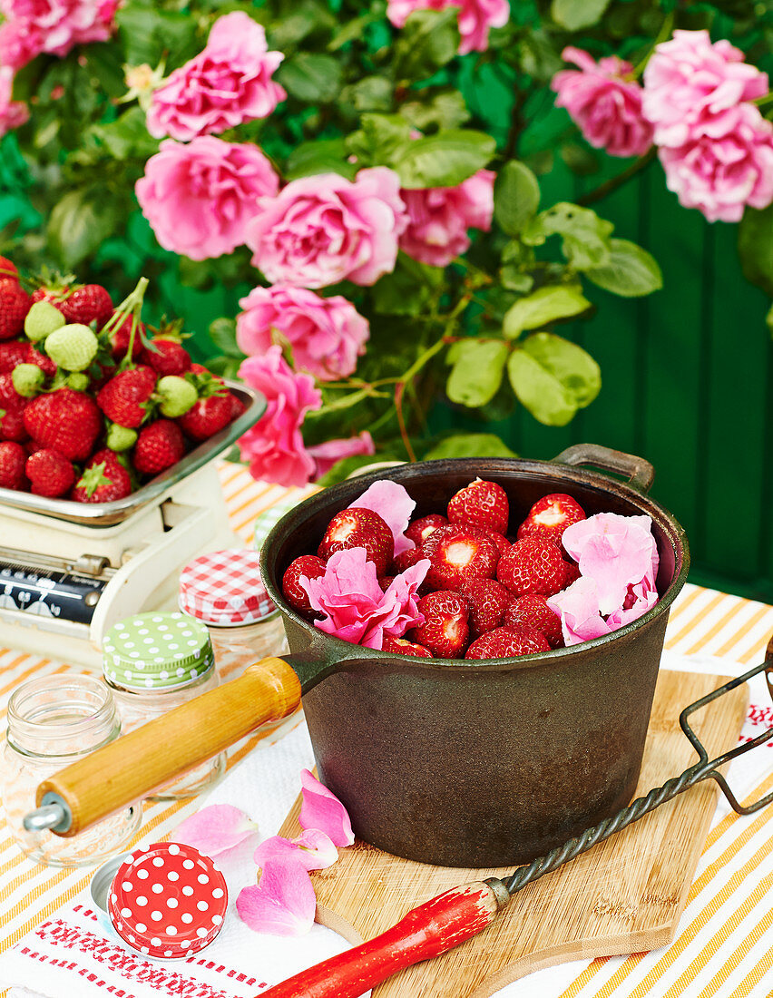 Frische Erdbeeren mit Rosenblüten im Topf