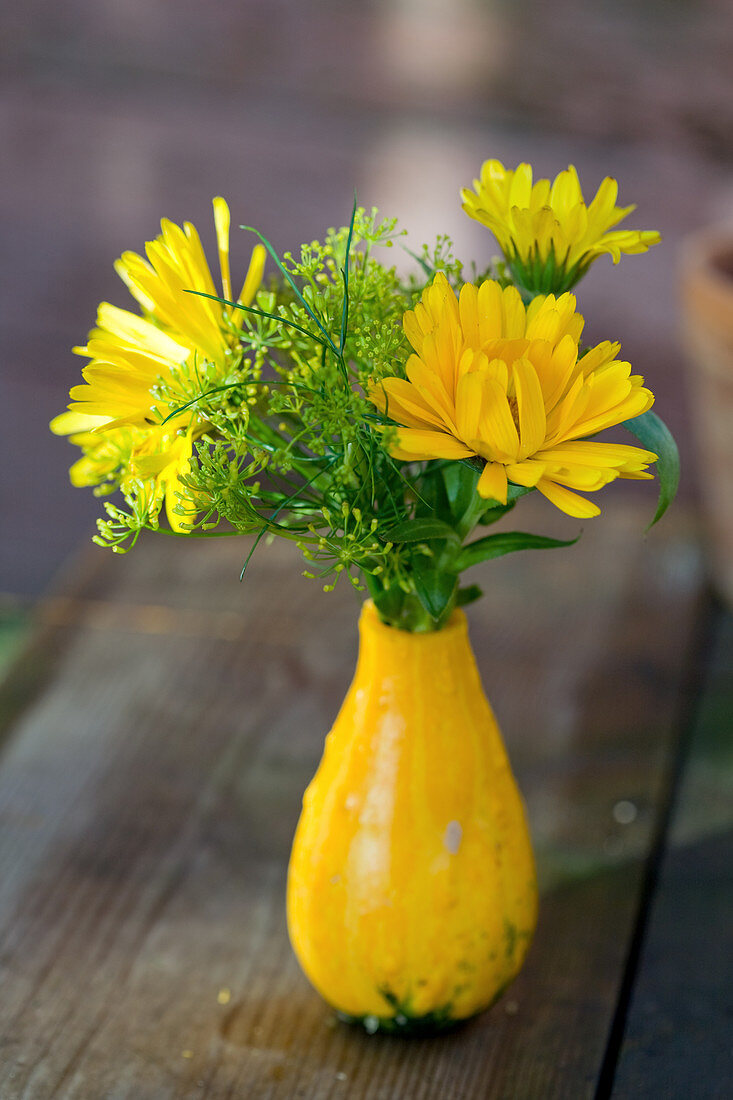 Kleiner Strauß aus Ringelblumen und Fenchelblüten in Zierkürbis als Vase