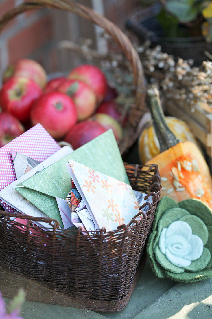 Körbchen mit selbstgefalteten Samentüten, Korb mit Äpfeln, Filzblüte