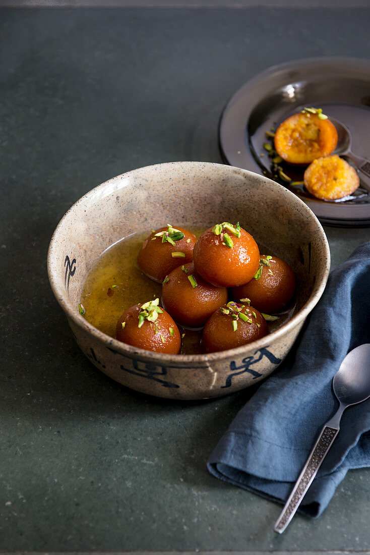 Indian dessert - Gulab Jamun with sweet sugar syrup and chopped pistachios